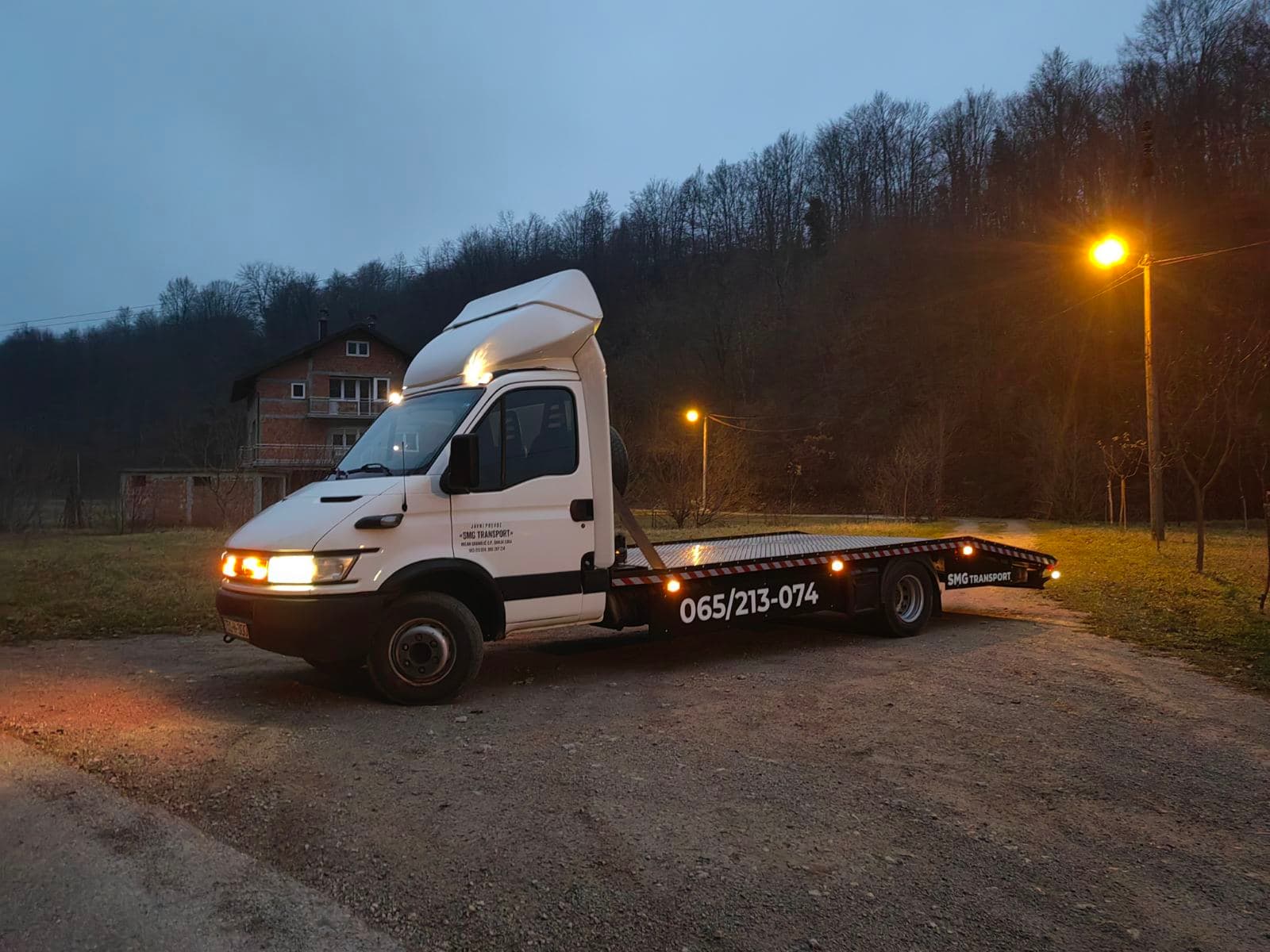 Šlep vozilo SMG Transport sa platformom za automobile, noću pod uličnom rasvjetom