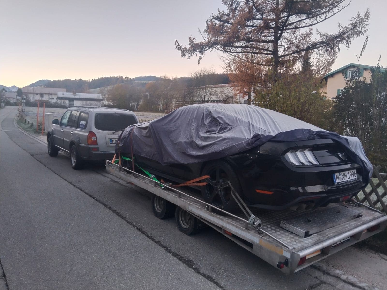 Pokriven sportski automobil učvršćen na prikolici za transport vozila