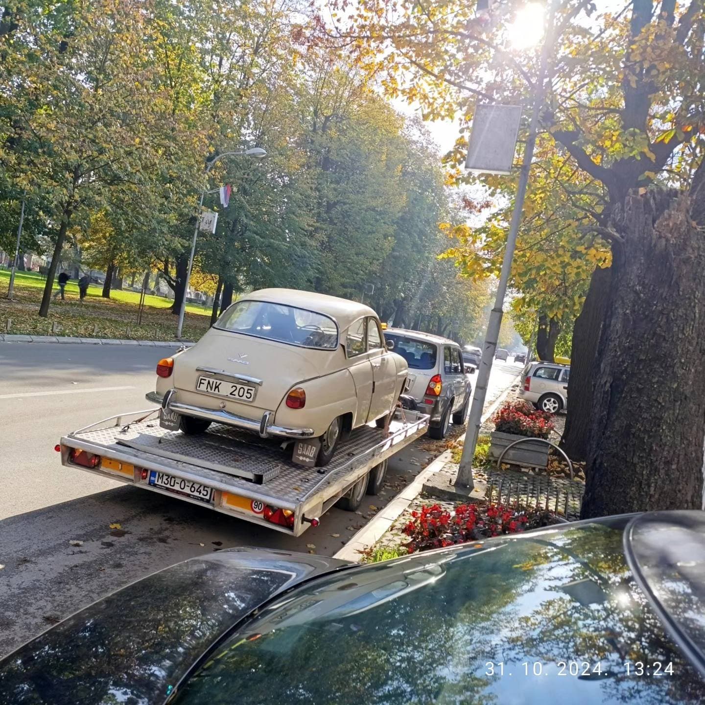 Oldtajmer na prikolici za transport vozila, parkiran uz drvored